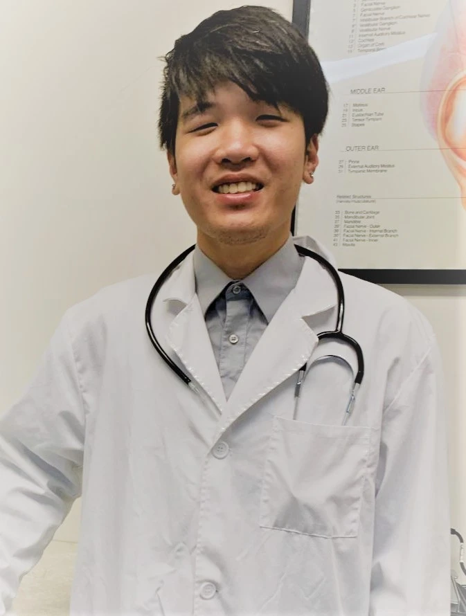 A Suncoast clinician in the Buena Park office beside an ear anatomy chart